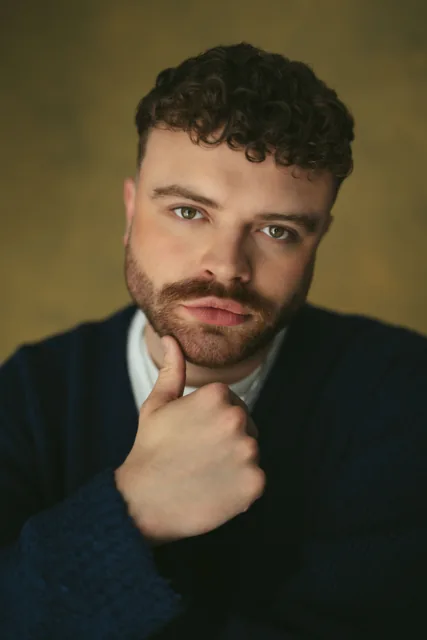 A sitter resting his chin on his hand against a neutral background.