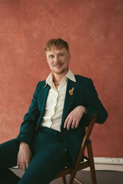 A seated portrait against a red studio background from the BBC commission.
