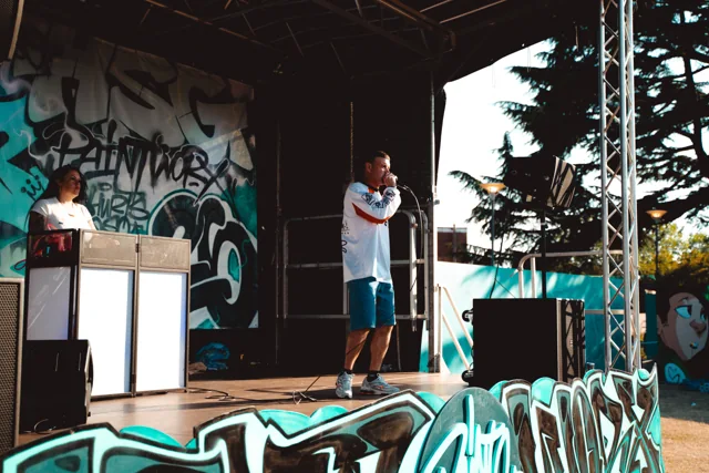 A performer on a stage with a brightly painted backdrop.
