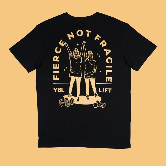 A black T-shirt styled against a mustard yellow background.