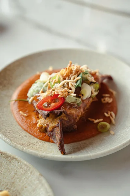 A plated dish with a golden crust, sliced chillies and spring onions.